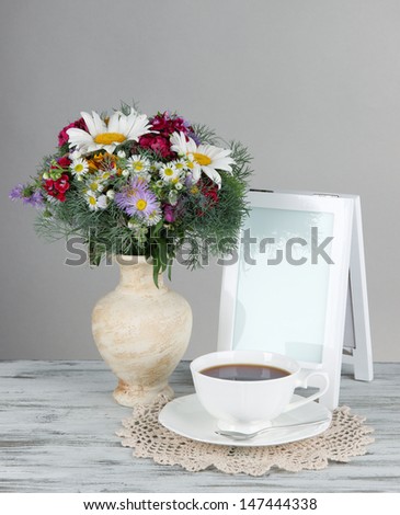 Beautiful bright flowers in vase on table on gray background