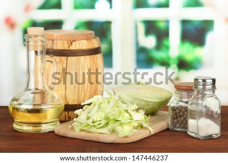 Green cabbage, oil, spices on cutting board, on bright background