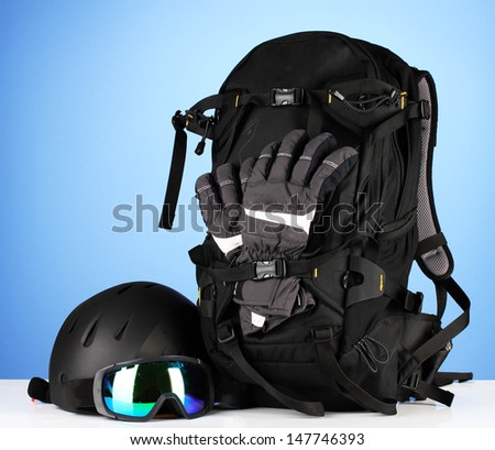 Winter sport glasses, helmet and gloves, backpack, on blue background