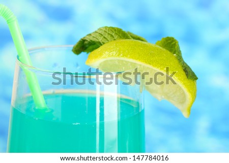 Glass of blue cocktail on blue background, close up