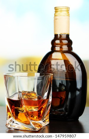 Glass of liquor with bottle, on dark background