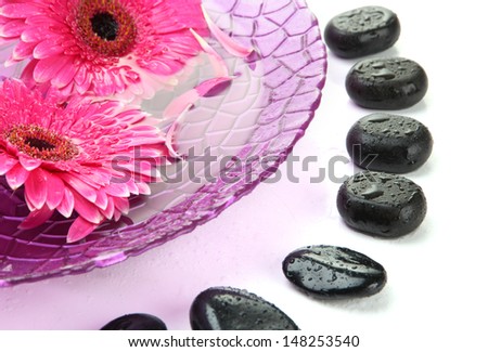 Spa stones and gerbera flowers on water, isolated on white