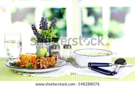 Soup and rice with meat in plates on napkin on tablecloth on room background