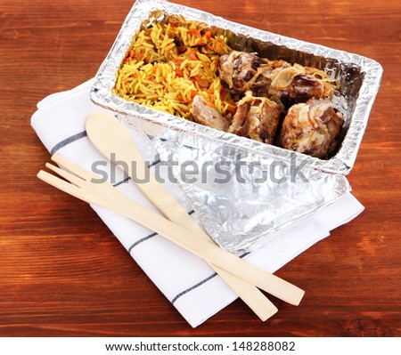 Food in box of foil on napkin on wooden background