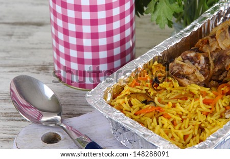 Food in boxes of foil on napkin on wooden board on wooden table