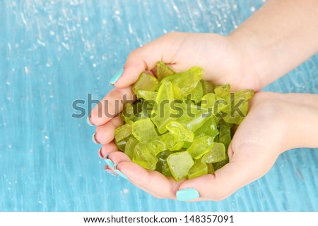 Beautiful woman\'s hands holding handful of sea salt, on color background