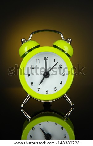 Green alarm clock on dark yellow background