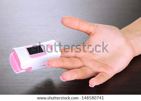 Pulse oximeter used to measure pulse rate and oxygen levels, on wooden background