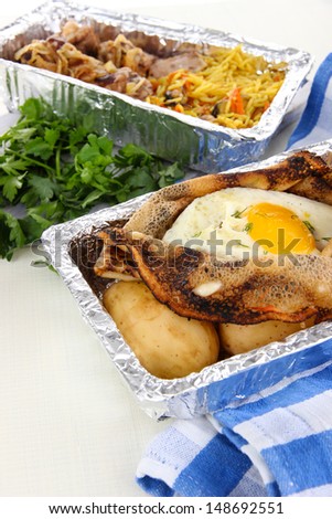 Food in boxes of foil on napkin on wooden board isolated in white