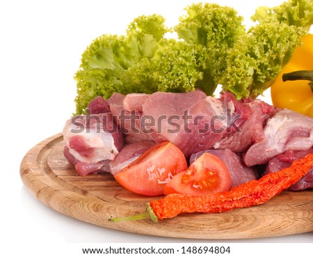 Pieces of raw meat and vegetables on wooden board isolated on white