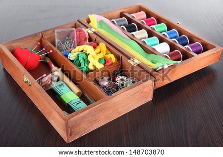 Sewing kit in wooden box on wooden table