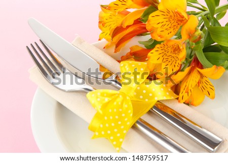 Festive dining table setting with flowers on pink background