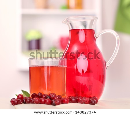 Pitcher and glass of cranberry juice with red cranberries on table