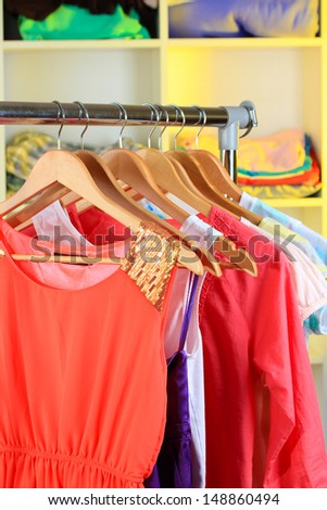 Variety of clothes on wooden hangers on shelves background