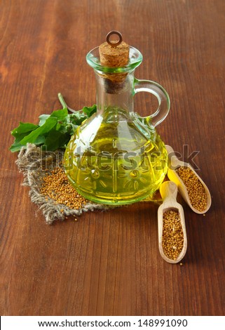 Jar of mustard oil and  mustard seeds on wooden background