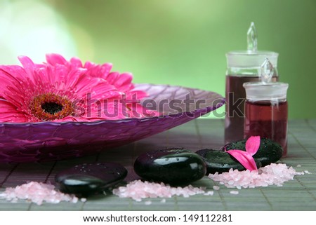 Gerbera flowers on water and spa stones on bamboo mat