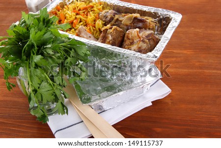 Food in boxes of foil on wooden background