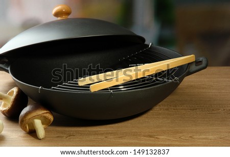 Black wok pan and vegetables on kitchen table, close up