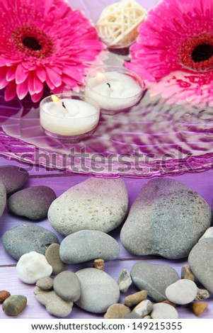 Beautiful gerbera flowers, stones and candles on water