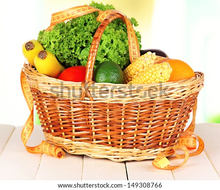 Fresh vegetables in wicker basket on table on light background