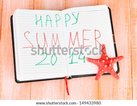Notepad with sign \'Happy summer\' Concept of vacation planning. On color wooden background