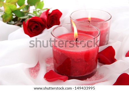 Beautiful candles with flowers on white cloth, close up