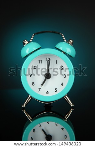 Blue alarm clock on dark blue background