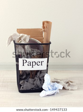 Assorted trash in bucket on room background
