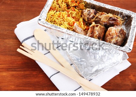 Food in box of foil on napkin on wooden background