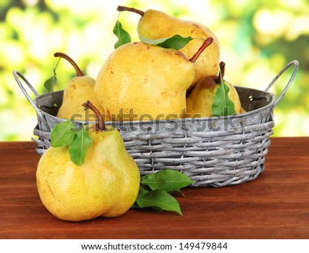 Juicy pears in wicker basket on table on bright background