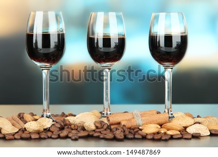 Glasses of liquors with almonds and coffee grains, on bright background