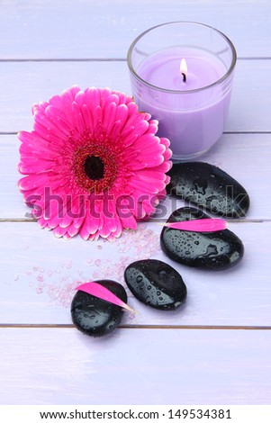 Spa stones, beautiful gerbera and candle on wooden table