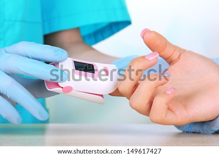 Doctor measuring pulse rate and oxygen levels, on bright background