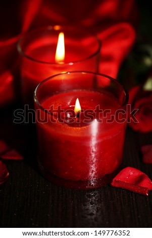 Beautiful romantic red candle with flowers and silk cloth, close up