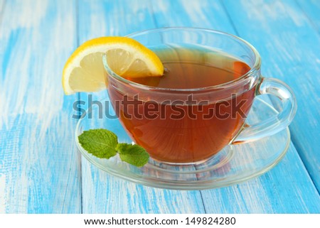 Cup of tea with lemon on table on blue background