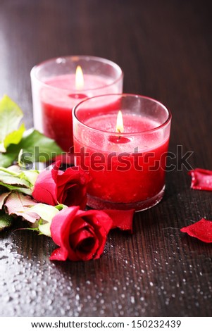 Beautiful romantic red candles with flowers on dark wooden background