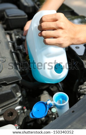 Man pours liquid for washing glasses to car