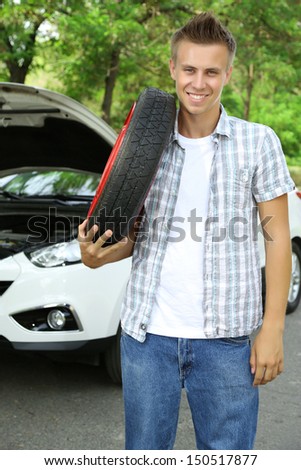 Man driver holding tire on shoulder