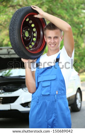 Auto mechanic with tire on his shoulder