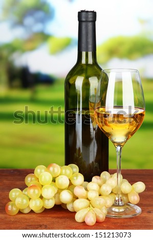 Ripe grapes, bottle and glass of wine, on bright background