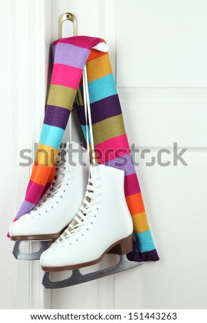 Figure skates hanging on a door knob with scarf