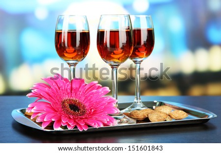 Glasses of amaretto liquor and roasted almonds, on tray, on bright background