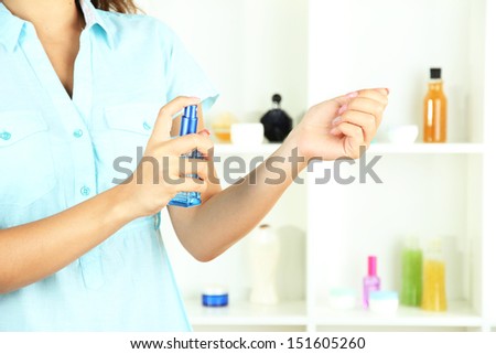 Woman testing perfume on shop windows background