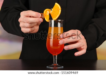 Bartender making and decorating cocktail on bright background, close-up