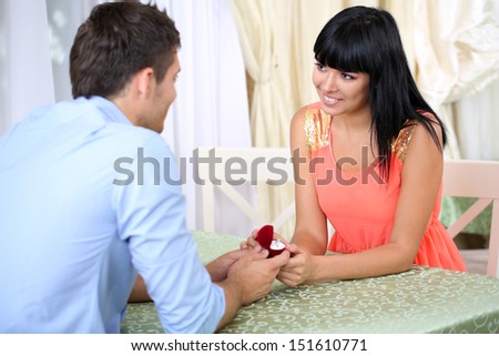 Man proposing engagement ring his woman in restaurant