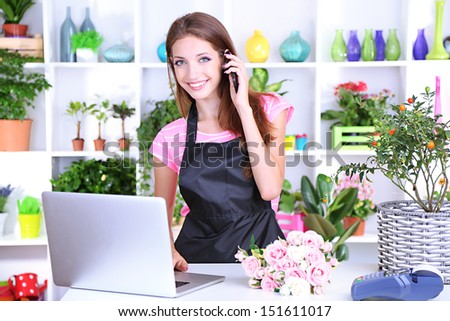 Beautiful girl florist with flowers in flowers shop