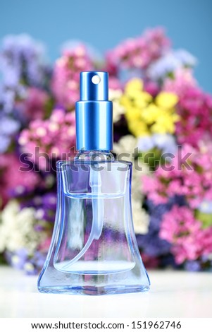 Women perfume in beautiful bottle and flowers on blue background