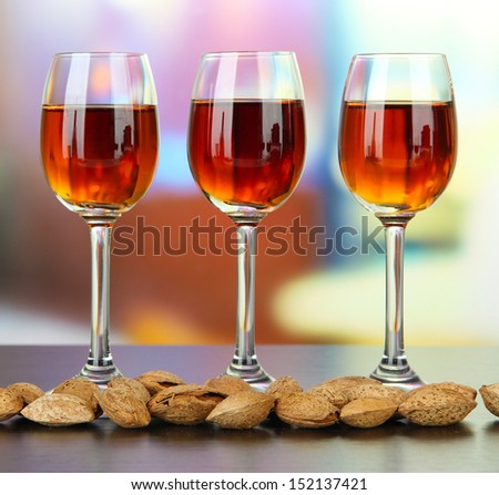 Glasses of amaretto liquor and roasted almonds, on bright background