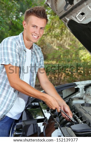 Young driver repairing car engine outdoors