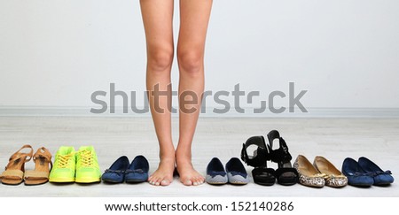 Girl chooses shoes in room on grey background